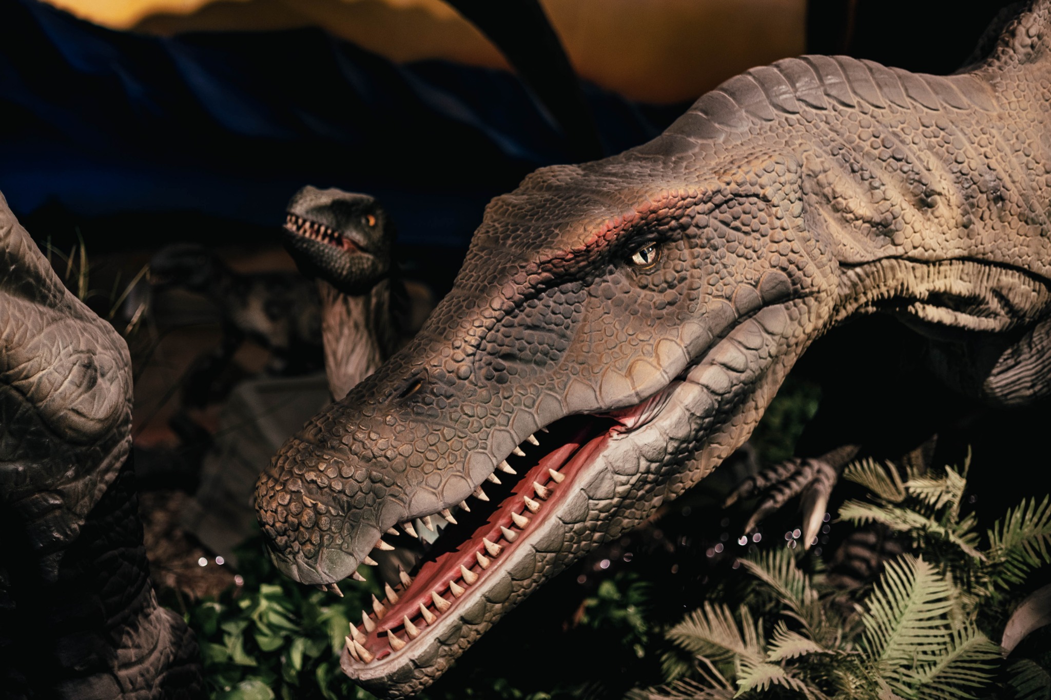 A large dinosaur model with bared teeth in foliage inside Ancient Restaurant Dinosaur in Yamato.