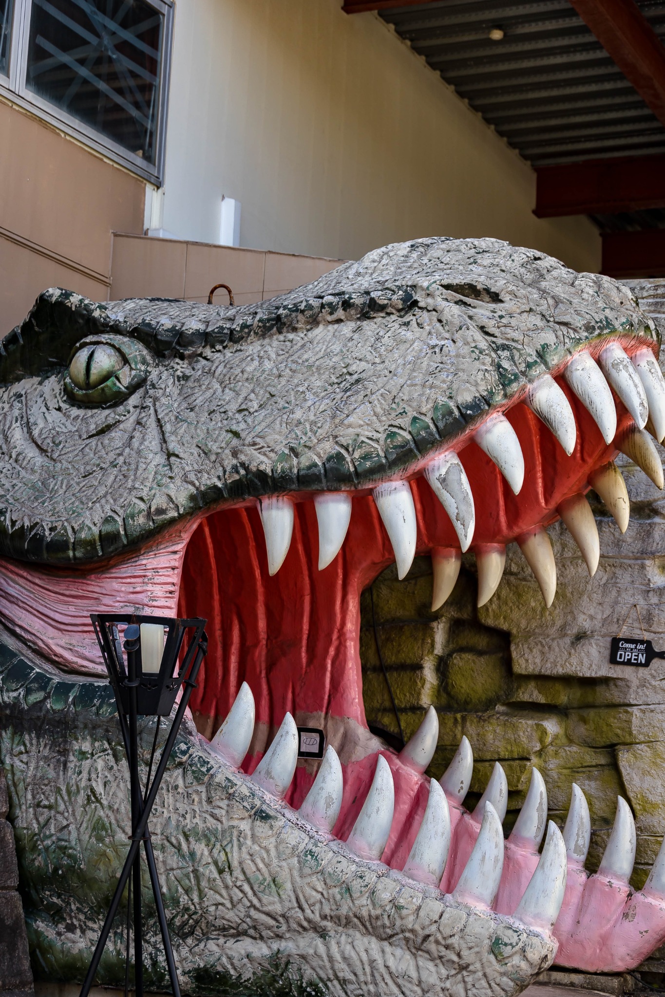 A giant dinosaur mouth frames the restaurant entrance beside a sign saying Come in.