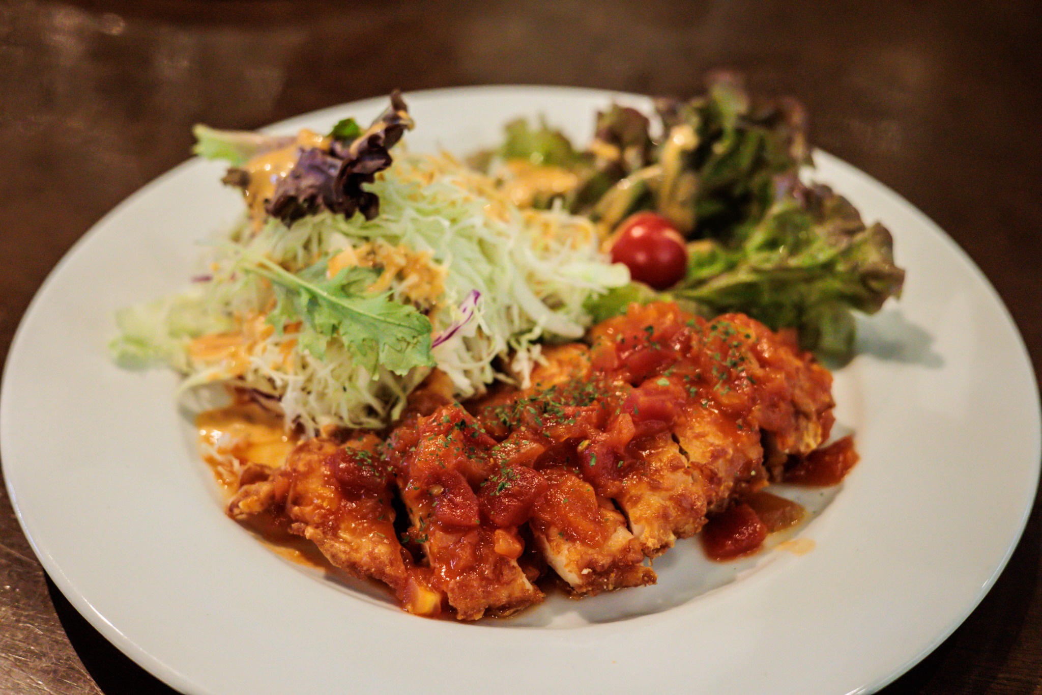 Chicken with tomato sauce and shredded cabbage salad on a plate.