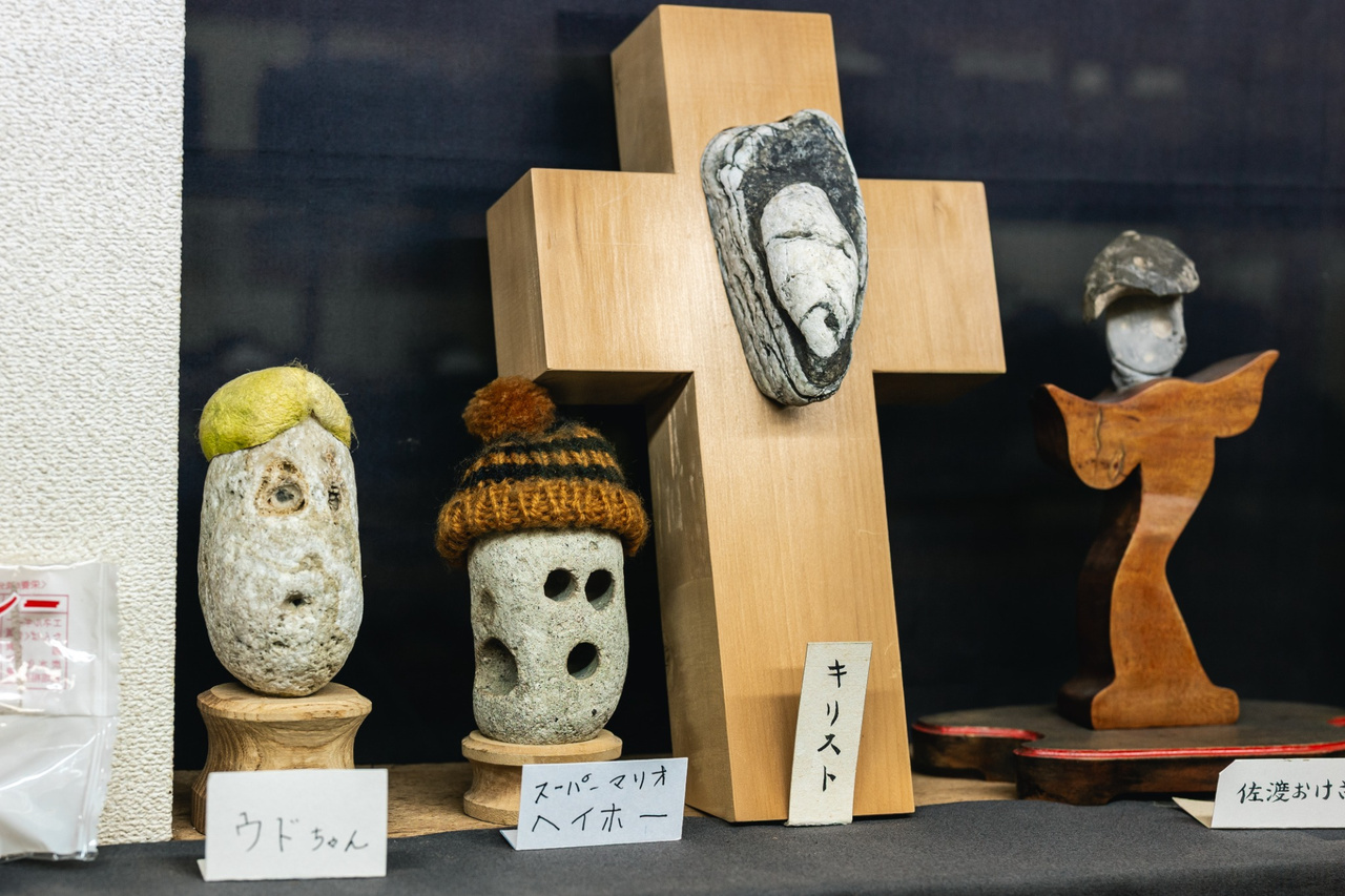 A face-like stone mounted on a wooden cross among other character stones.