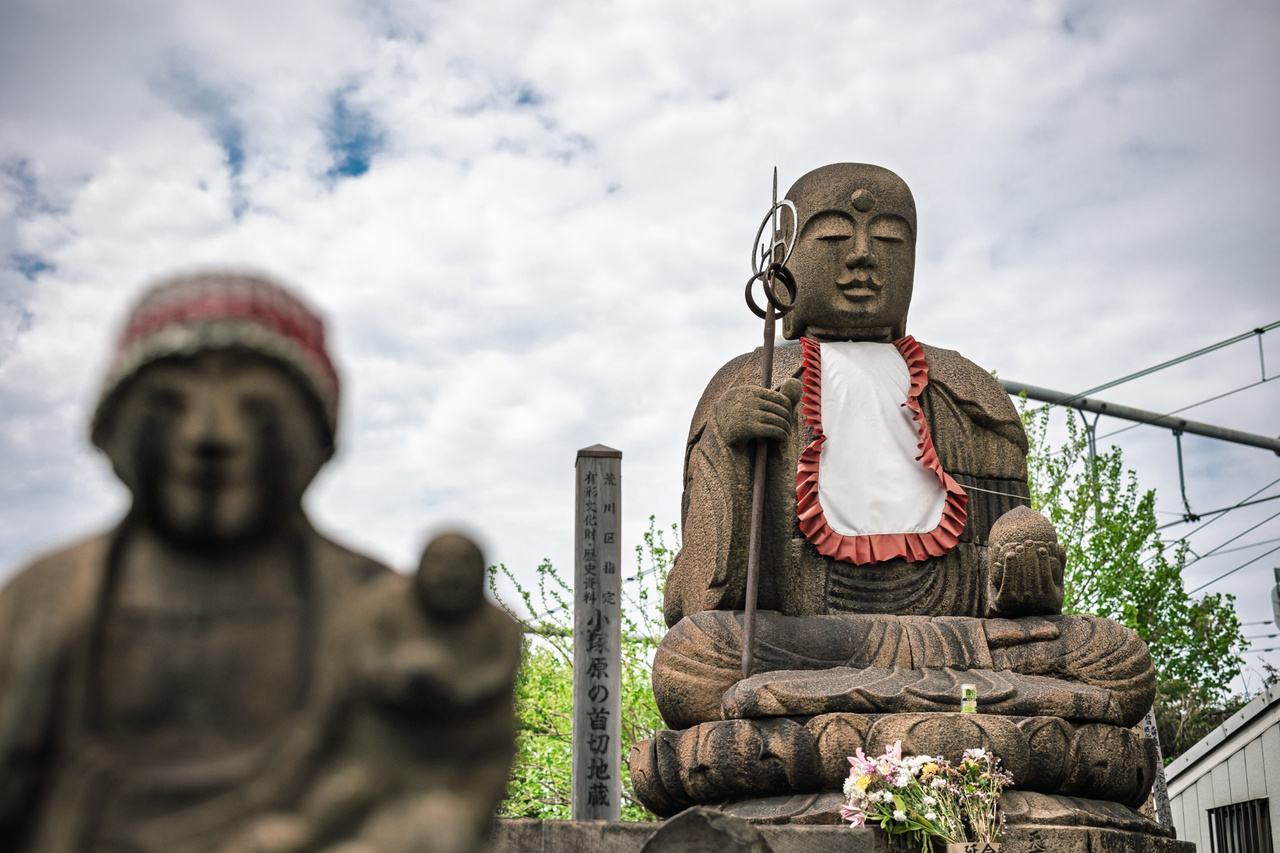 The large Kubikiri Jizō rising behind smaller stone Jizō figures in the grounds of Enmeiji Temple.