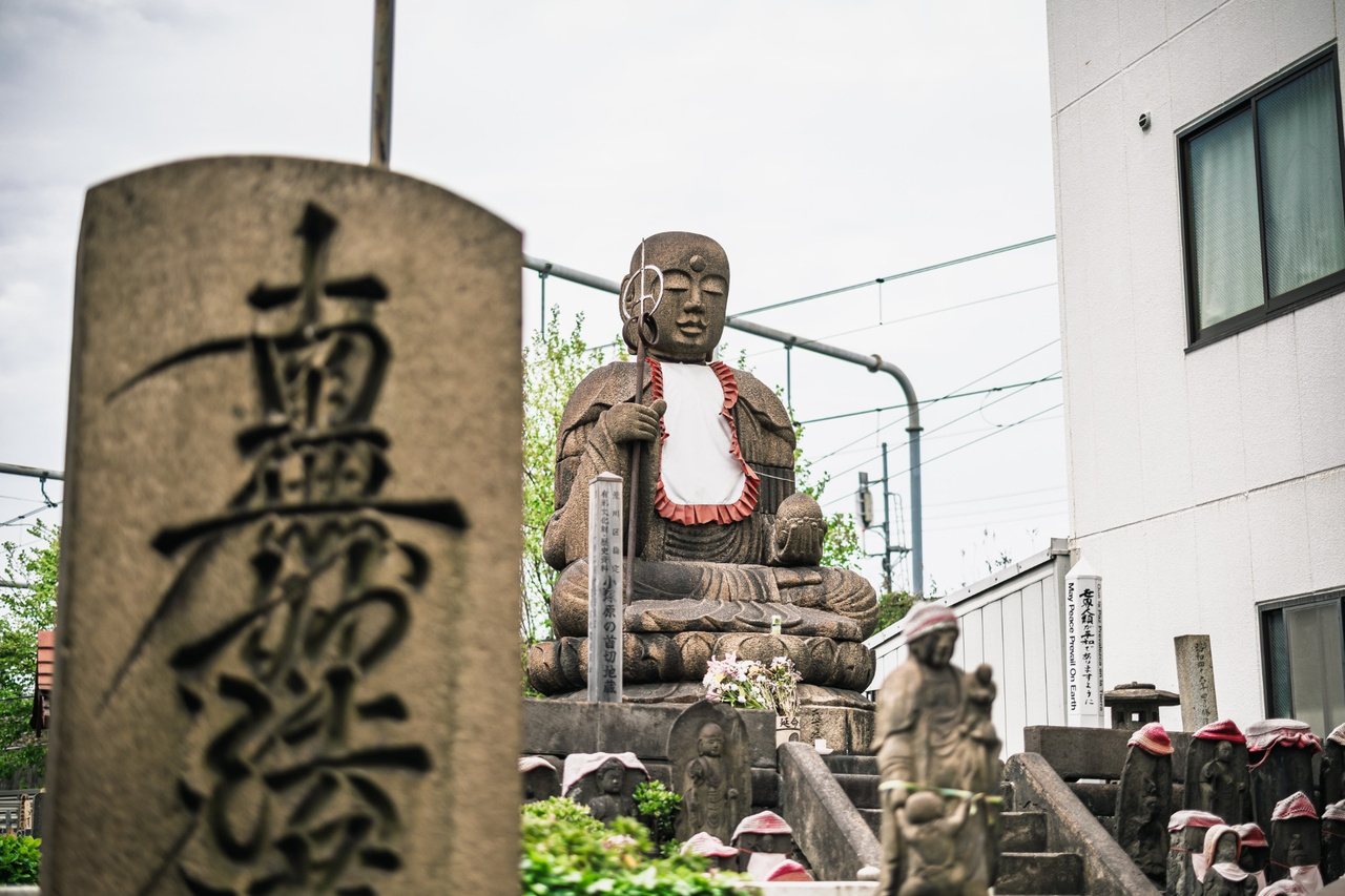 A stone Daimoku-tō monument dated 1698 in the foreground, with the Kubikiri Jizō behind it at Enmeiji.