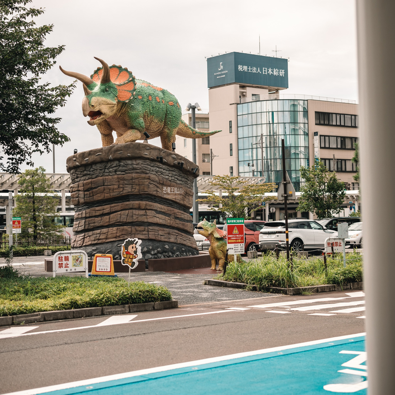 Full-scale parent Triceratops monument with a smaller child Triceratops beside it outside Fukui Station.
