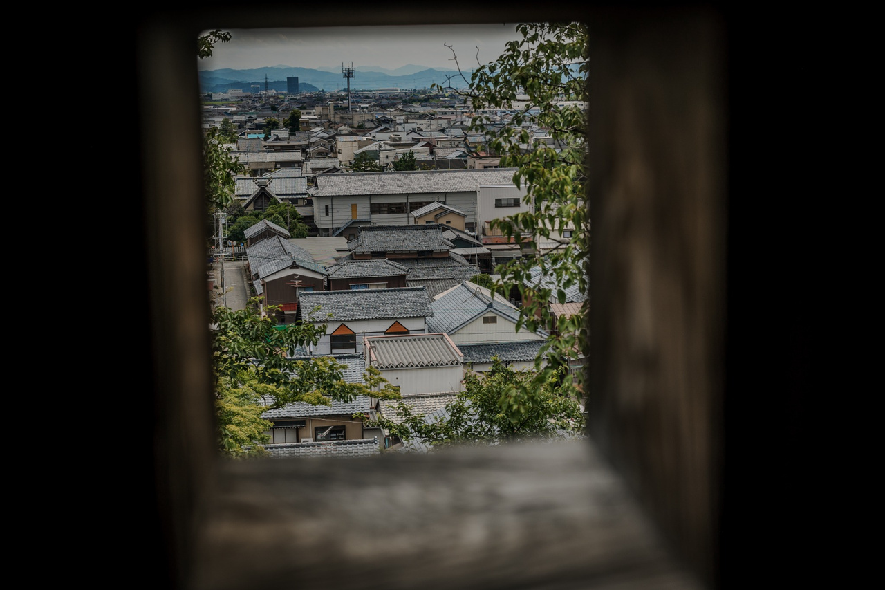 View of modern Maruoka through a dark wooden opening inside Maruoka Castle keep.
