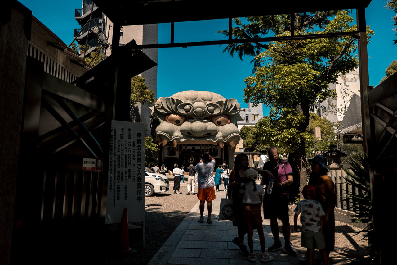 The giant open-mouthed Shishi-den seen through the entrance area of Namba Yasaka Shrine, with visitors in the courtyard.