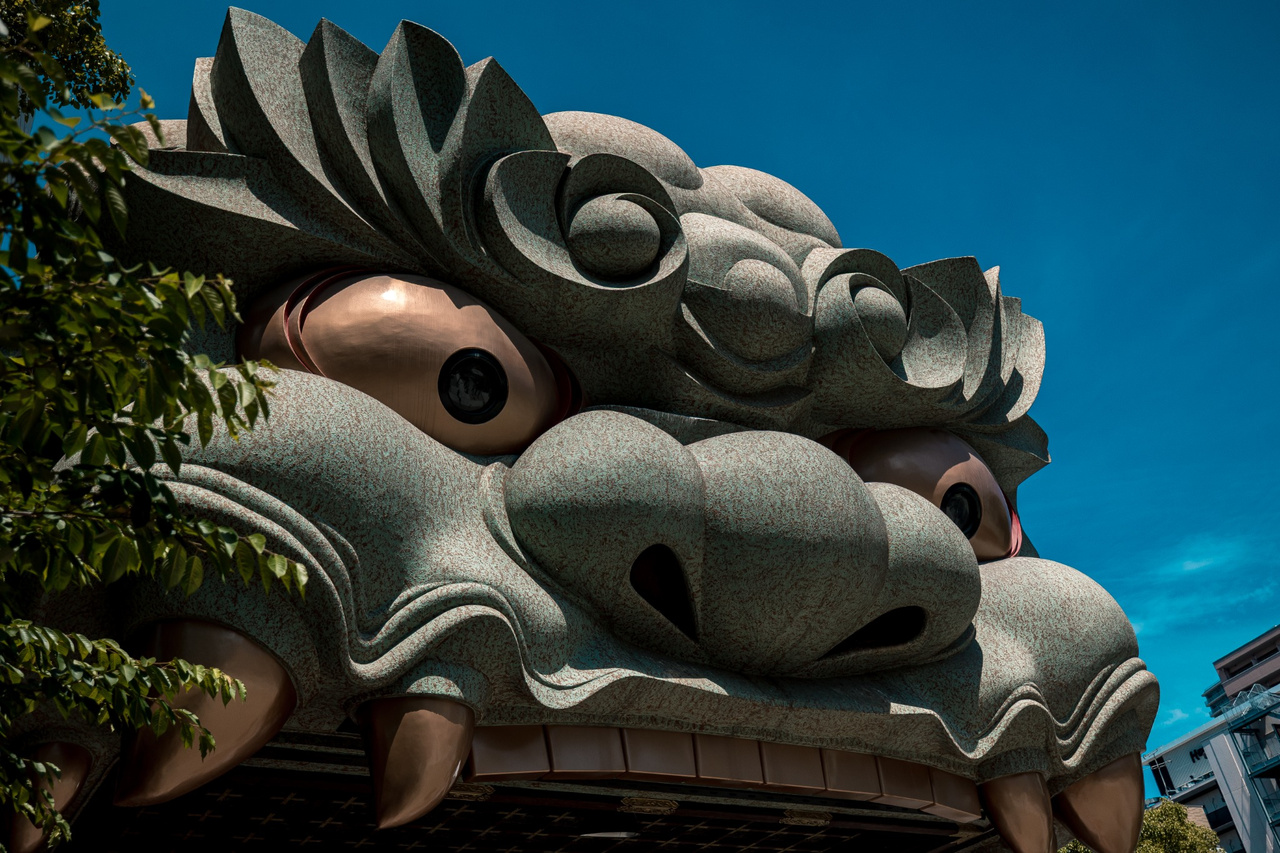 Close view of the Shishi-den's giant grey lion face, brass teeth, eyes and nose at Namba Yasaka Shrine.