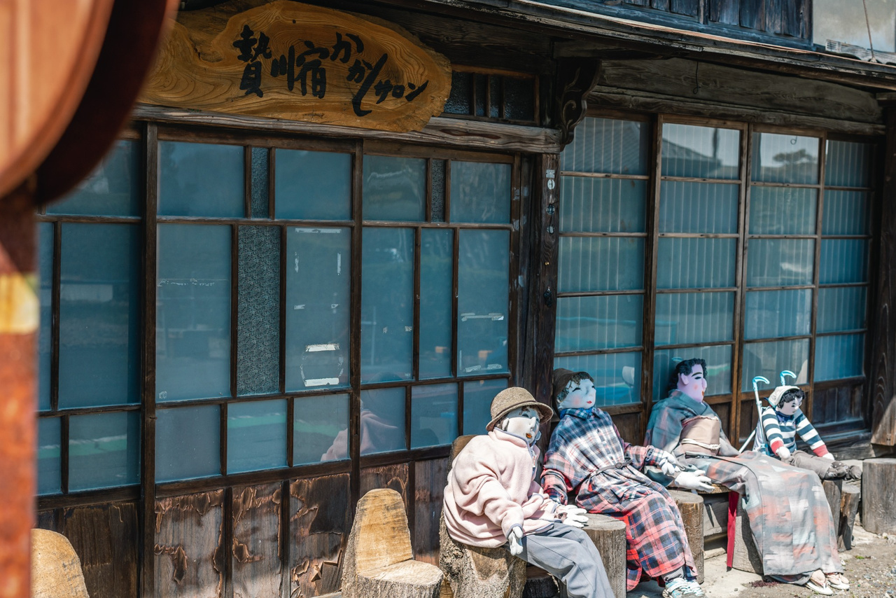 Several handmade scarecrows gather outside the Kakashi Salon in Niegawa-juku.