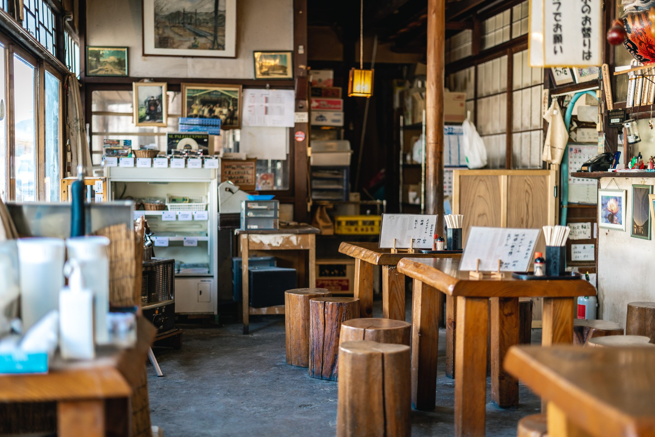 Wooden tables and log stools inside Fukushimaya, with framed photographs and railway memorabilia around the room.