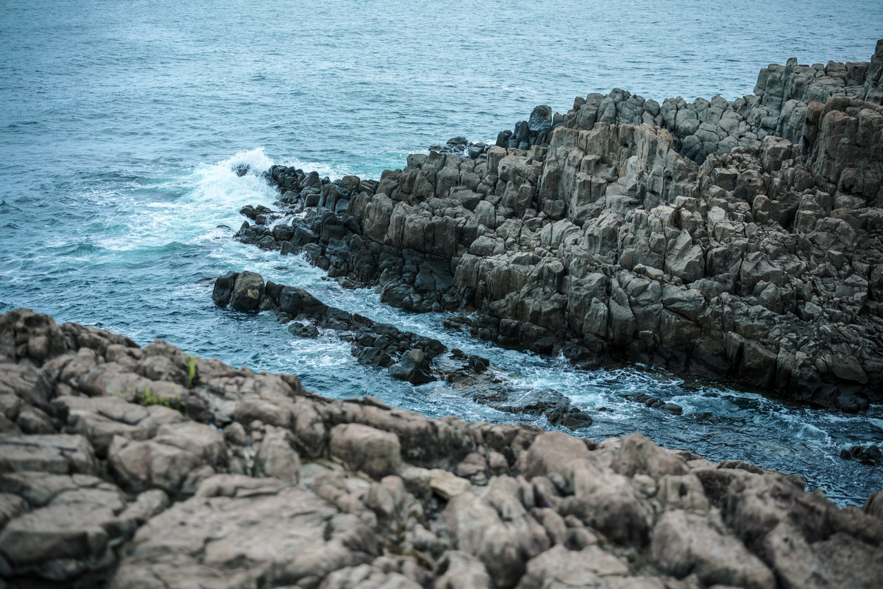 Waves breaking against the dark columnar cliffs of Tojinbo.