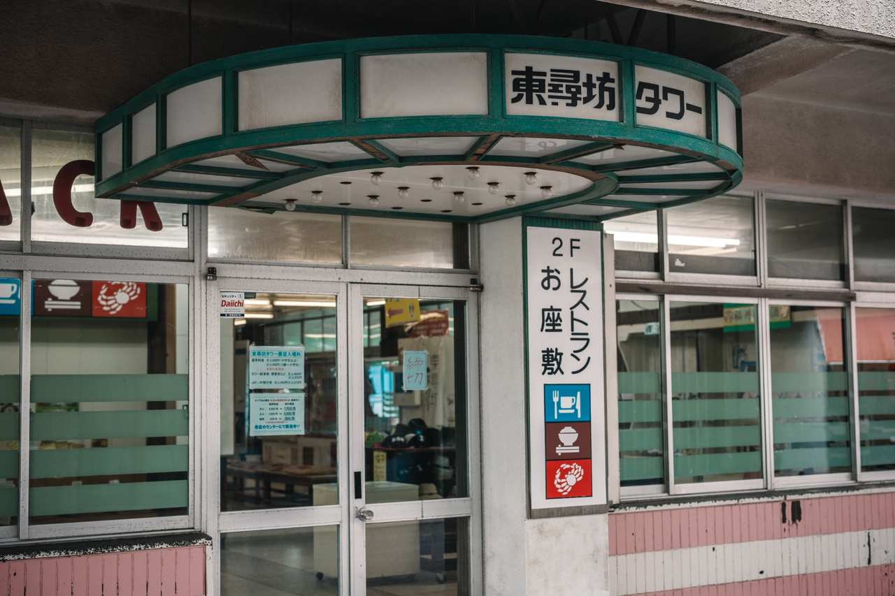 Entrance to Tojinbo Tower with older signage and the tower structure rising above it.