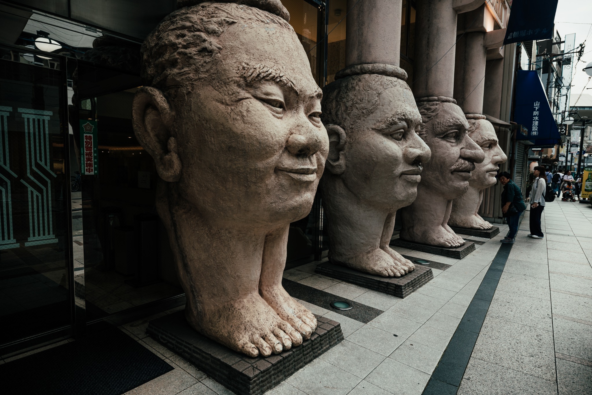 Four giant face-and-feet sculptures lined up outside the entrance to Dotonbori Hotel in Osaka.