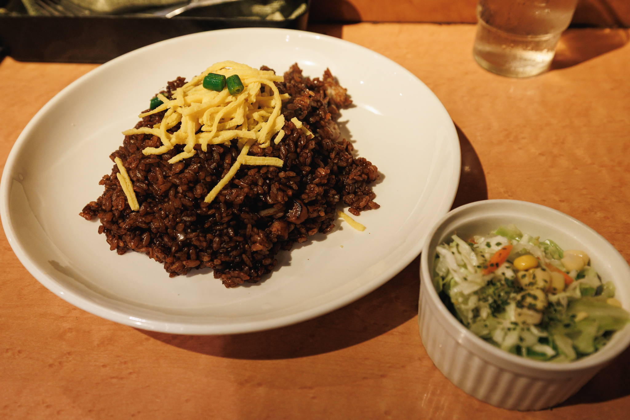 Dark ebimeshi topped with shredded egg and green onion at Indeira in Shibuya, with a small bowl of coleslaw beside it.