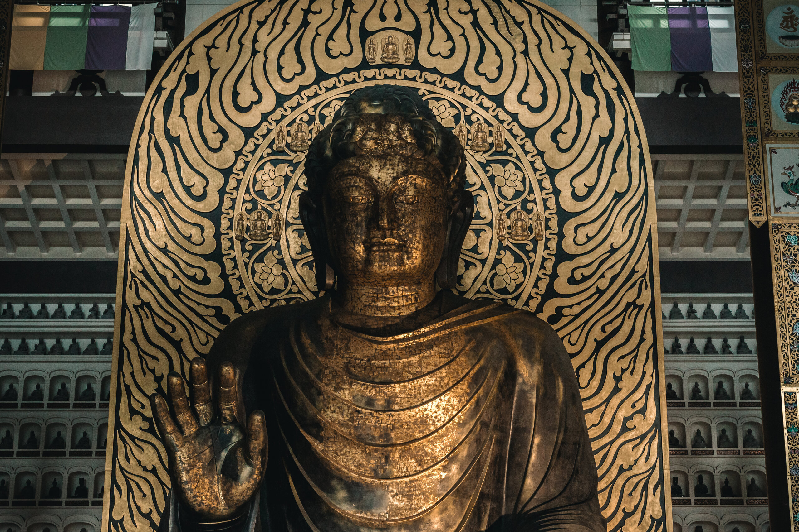 The Echizen Daibutsu seated before its gold-and-black halo, one hand raised.