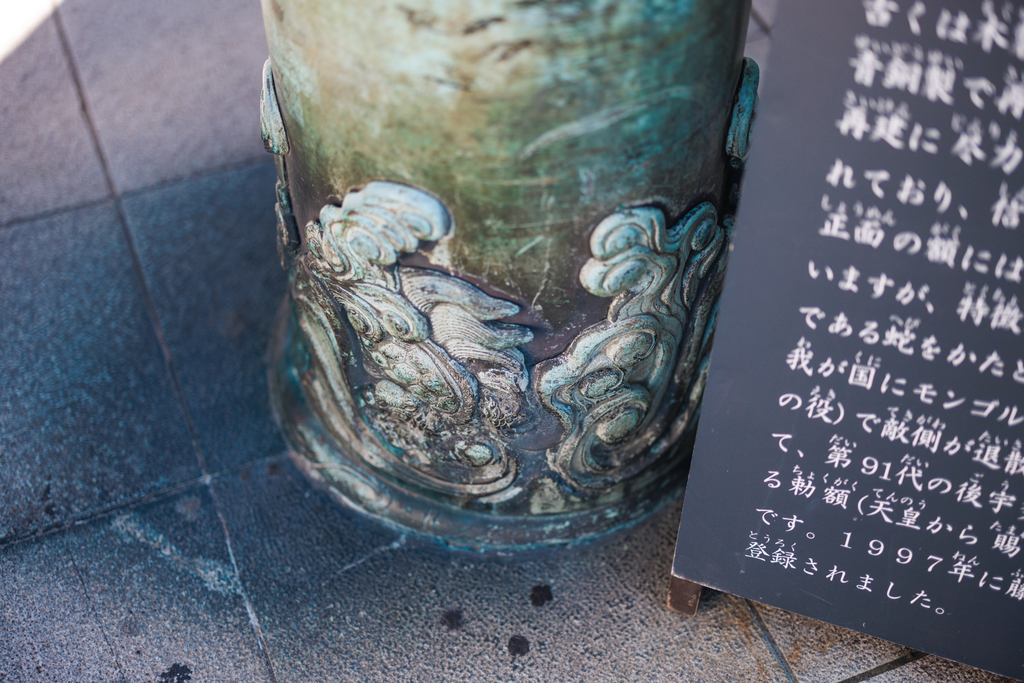Bronze waves and swirls in relief around the foot of one of the torii’s pillars