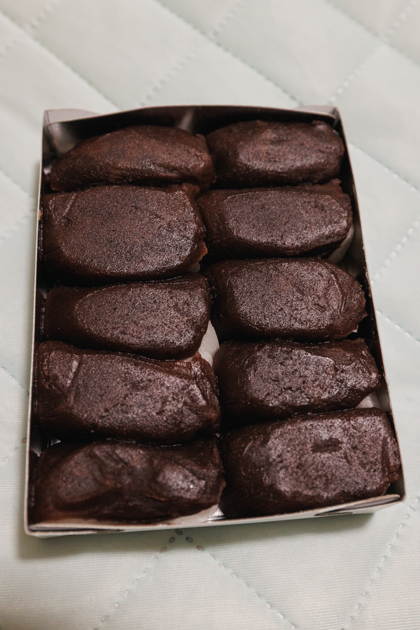 An open box of ten Gongorō chikara mochi covered in sweet bean paste.