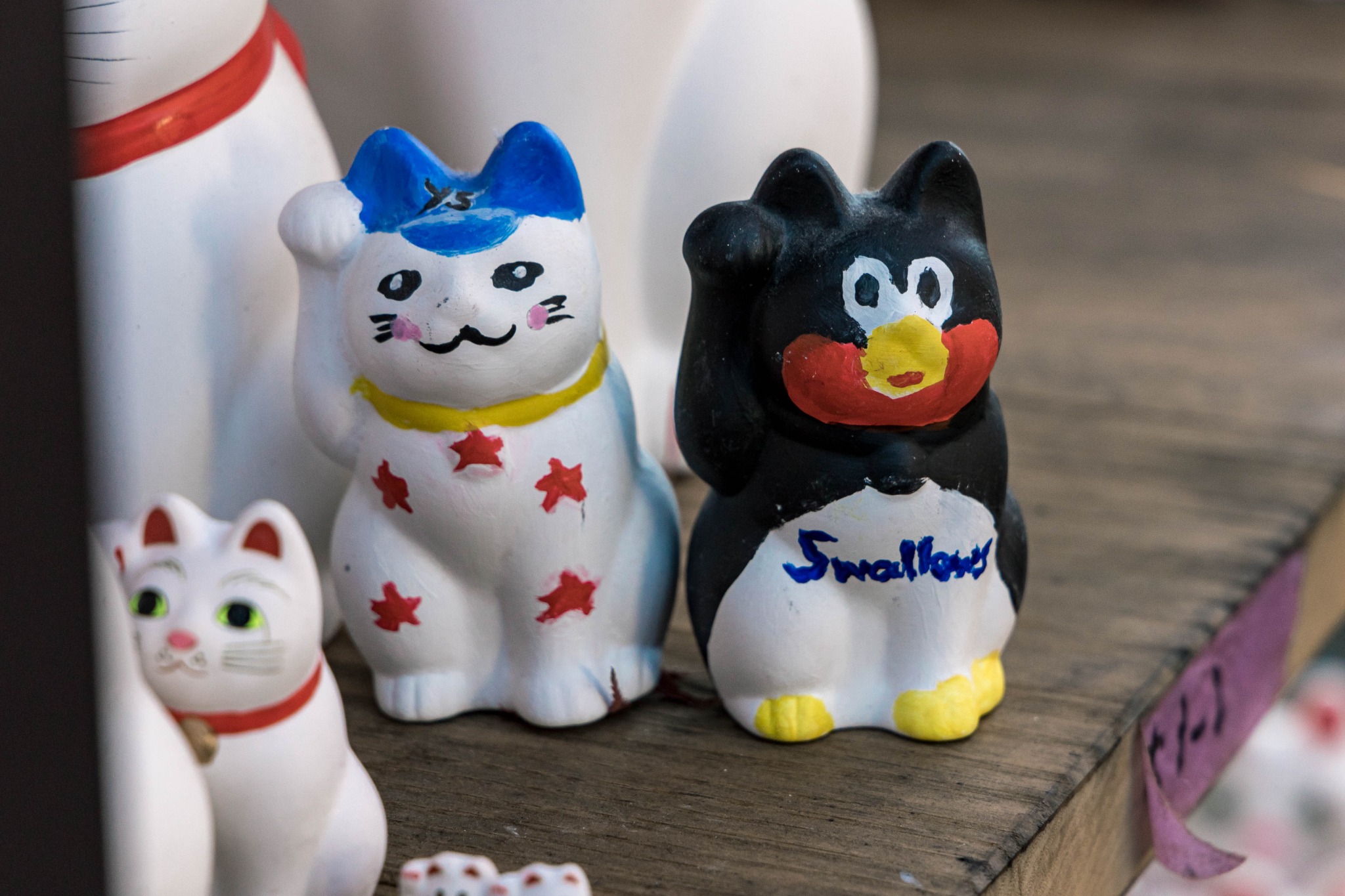 A maneki-neko figure photographed at Gotokuji in 2022 with visitor-added markings on its face and body.