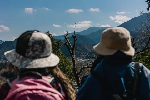 Two scarecrows in hats and backpacks look towards the mountains beyond Niegawa-juku in Chichibu.