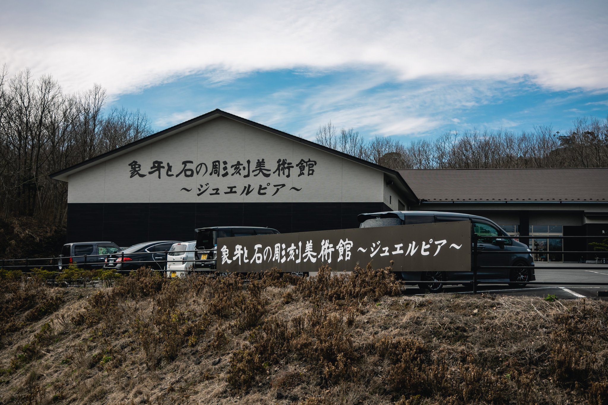 Jewelpia’s plain single-storey building, with the museum’s name on its wall and on a sign in front.