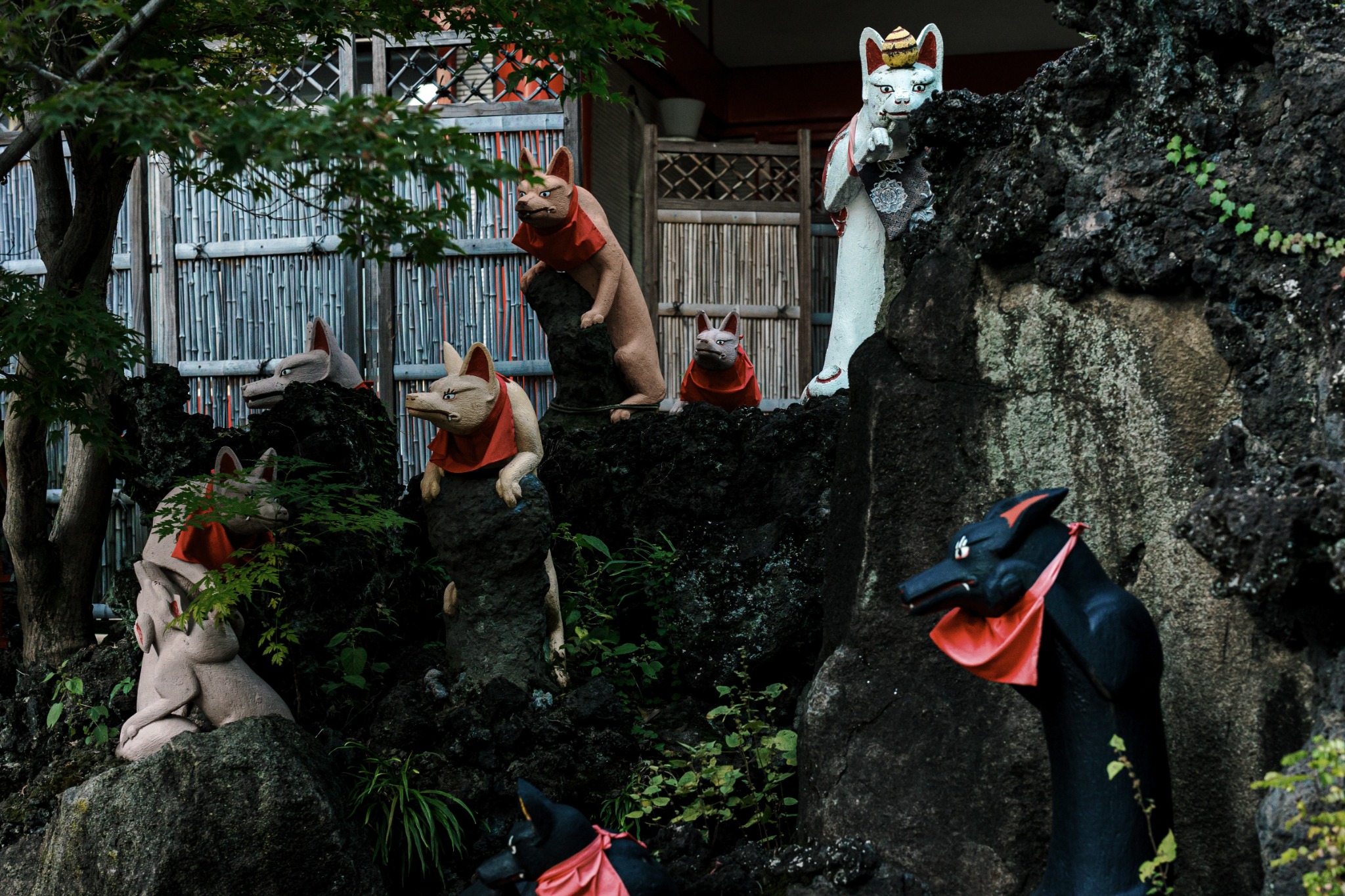 Black and white fox statues in different poses at Keihin Fushimi Inari Shrine.