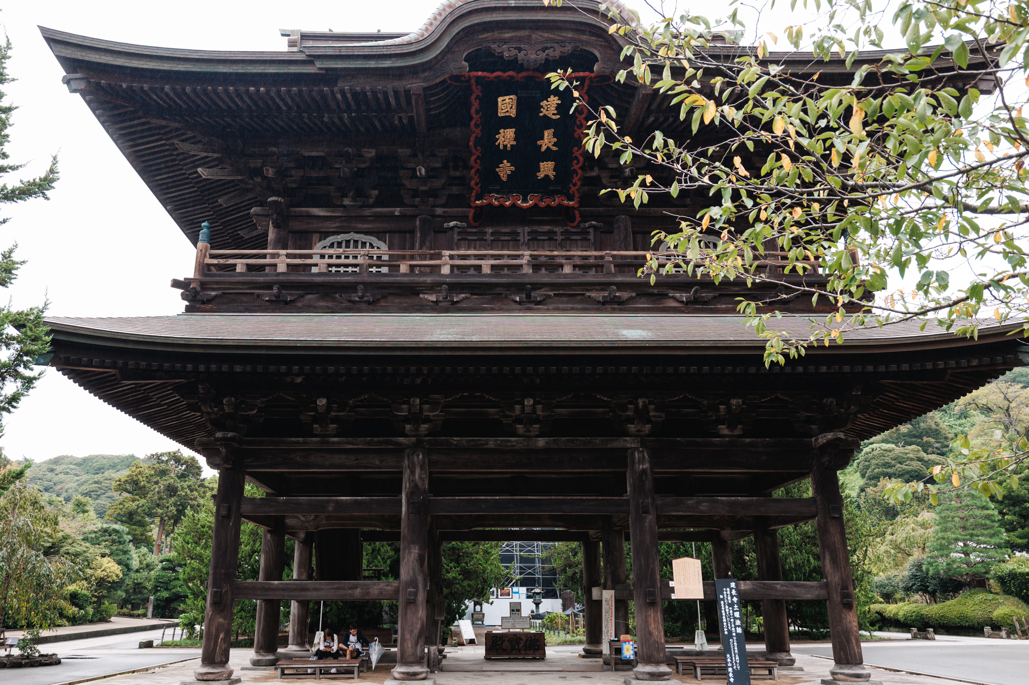Visitors standing beneath the wooden Sanmon gate at Kenchōji Temple in Kamakura.