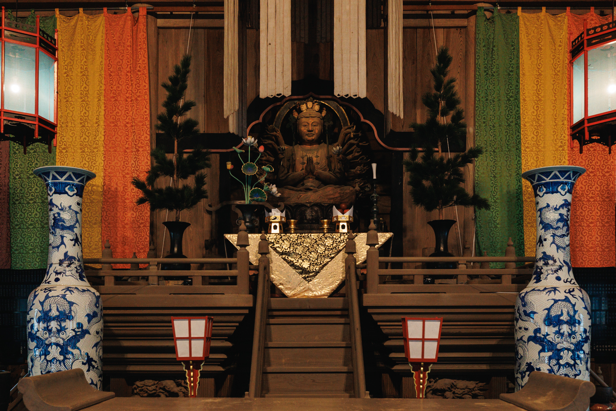 A Thousand-Armed Kannon beneath the Dharma Hall ceiling, flanked by blue-and-white vases painted with dragons.