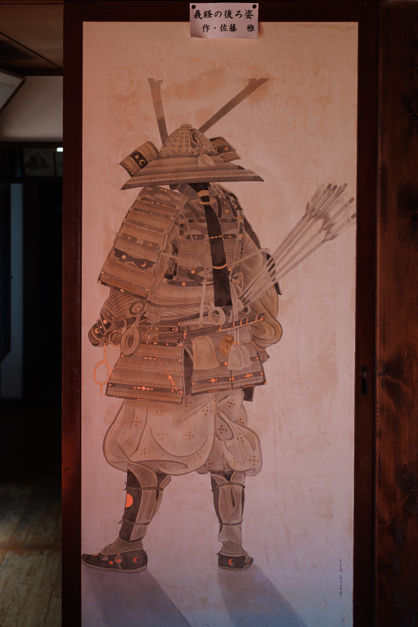 A sliding door painted with a warrior in full armour seen from behind, a quiver of arrows on his back, under a small title label