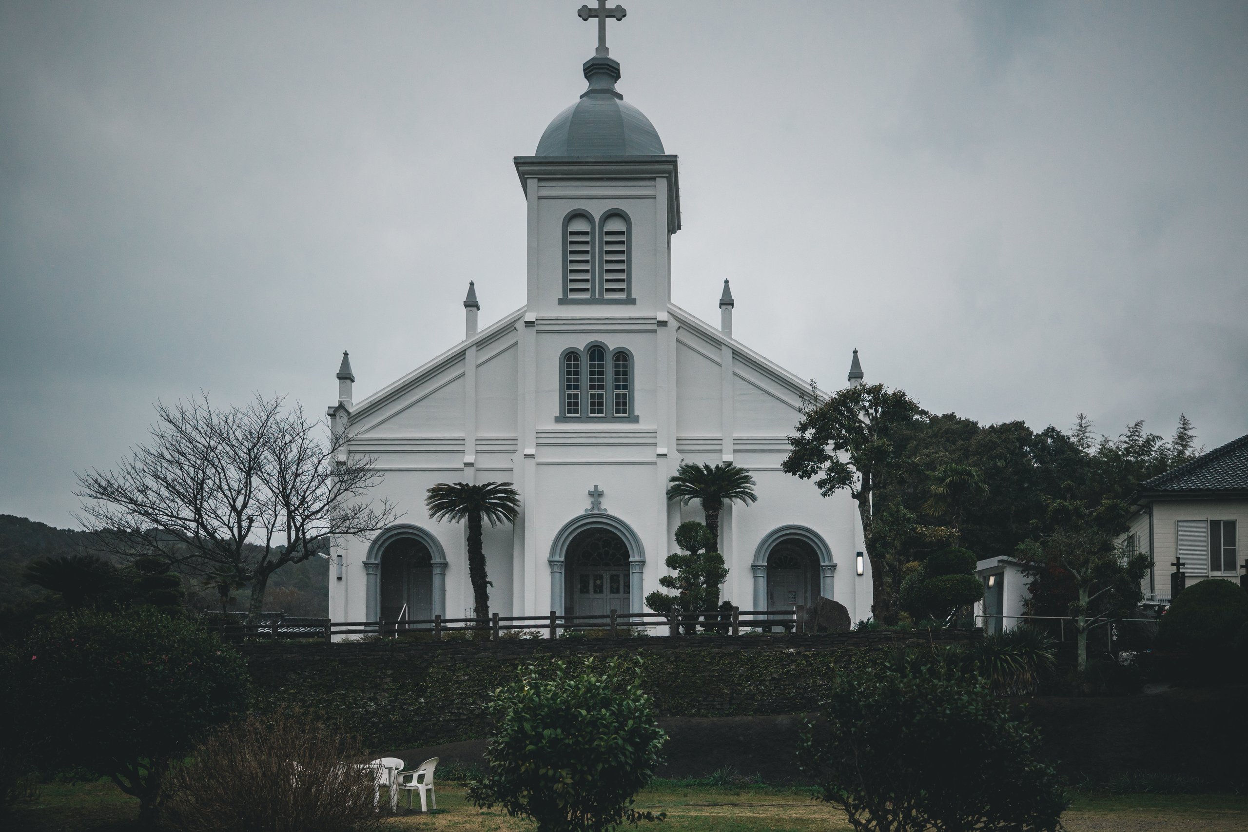 White façade, three arched entrances and a domed tower at Ōe Catholic Church in Amakusa.