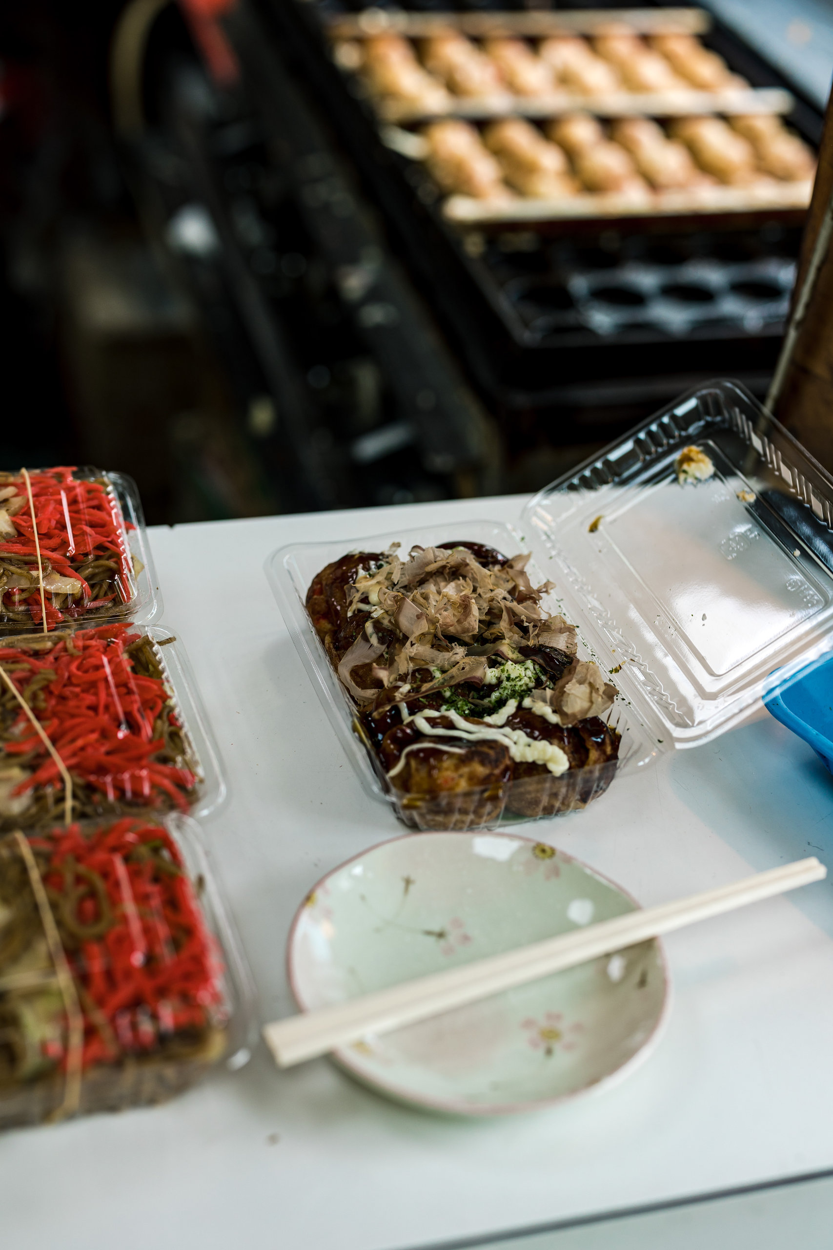Takoyaki beside a small plate and chopsticks at Power Blend Tanaka.