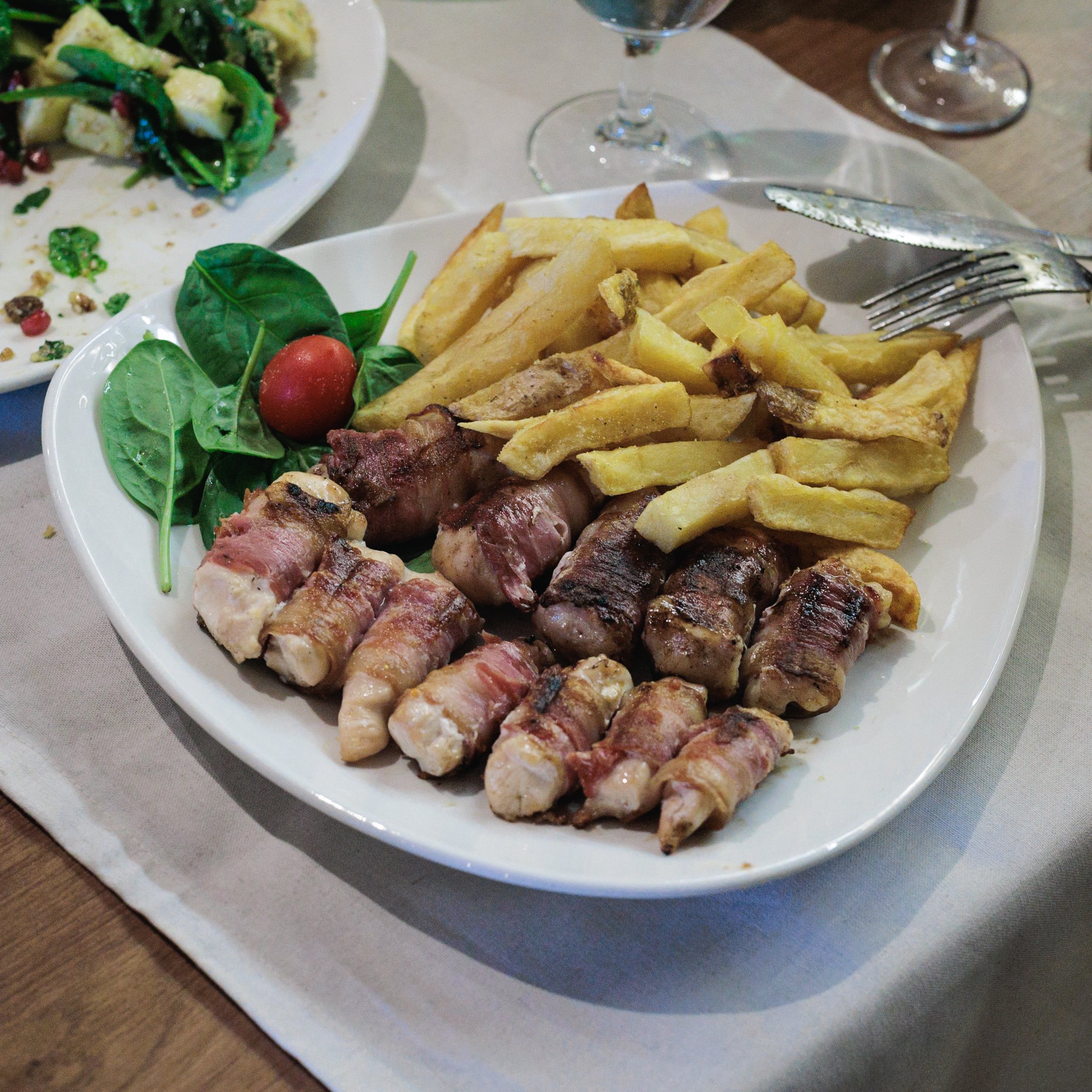Bacon-wrapped chicken skewers with thick-cut fries on a plate at Restoran Vidin Kapija in Niš.