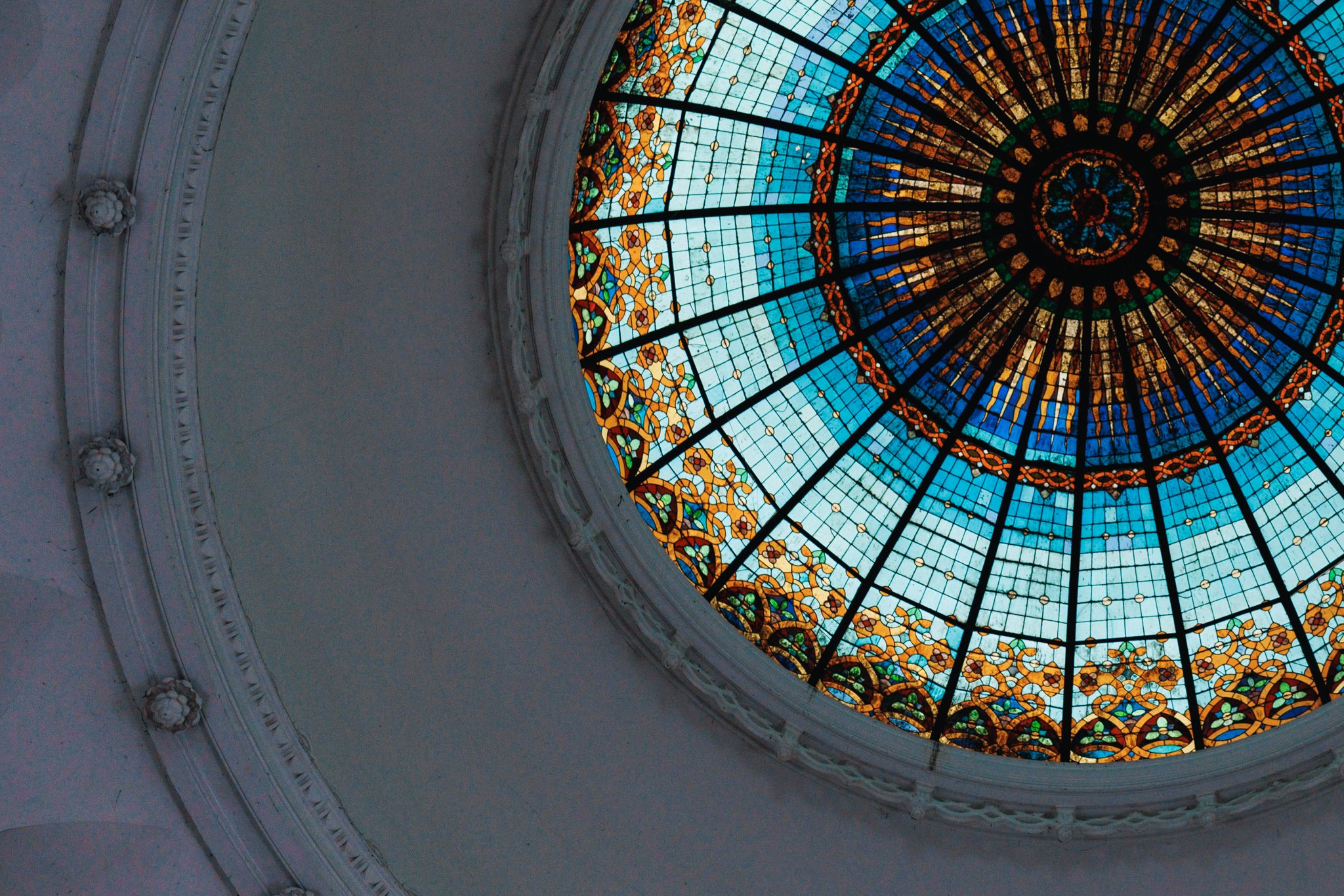 Blue and gold circular stained glass above the hall of Novi Sad Synagogue, framed off-centre.