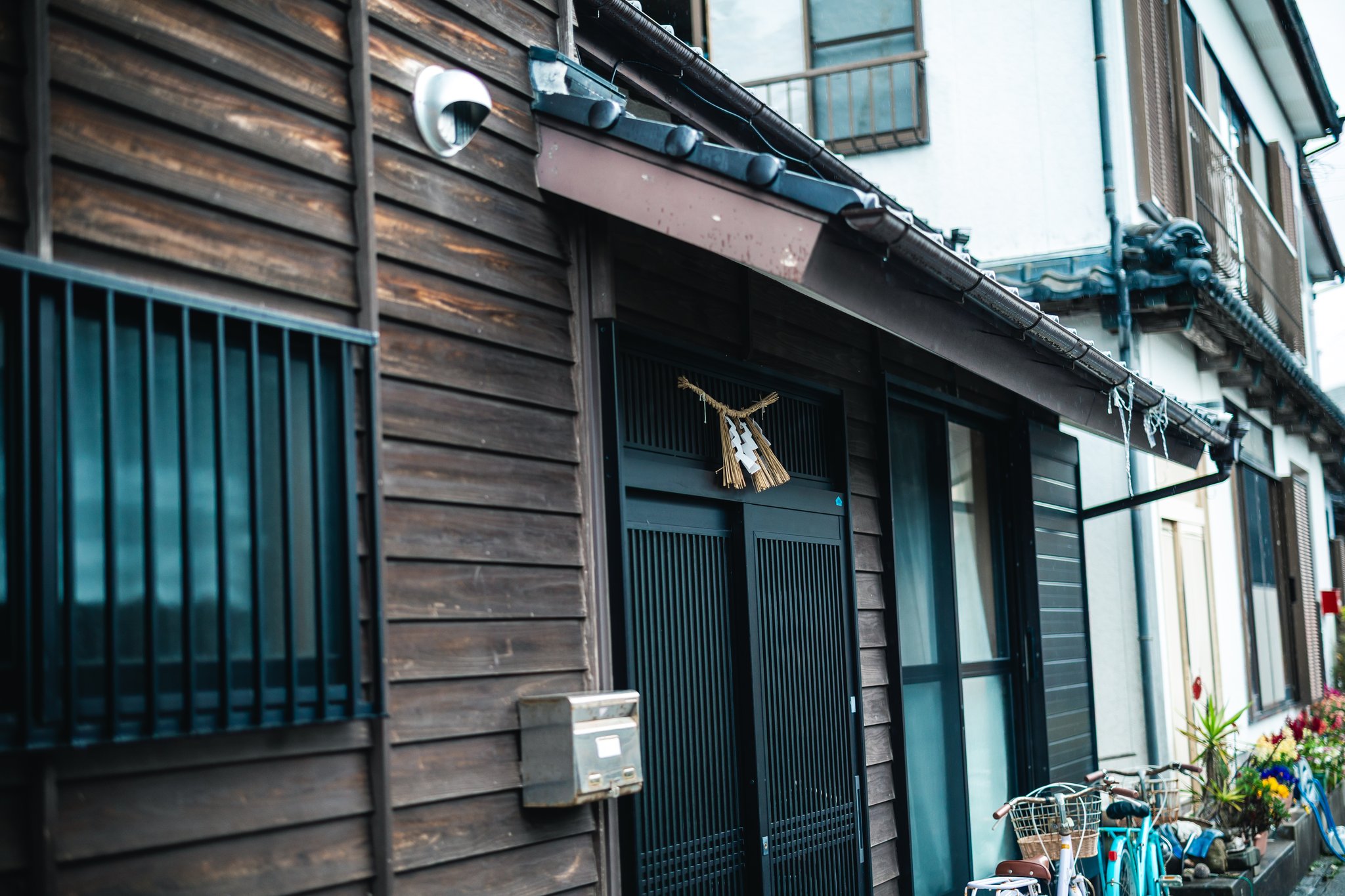 A straw shimenawa rope with paper strips hanging over the sliding door of a wooden house in Sakitsu