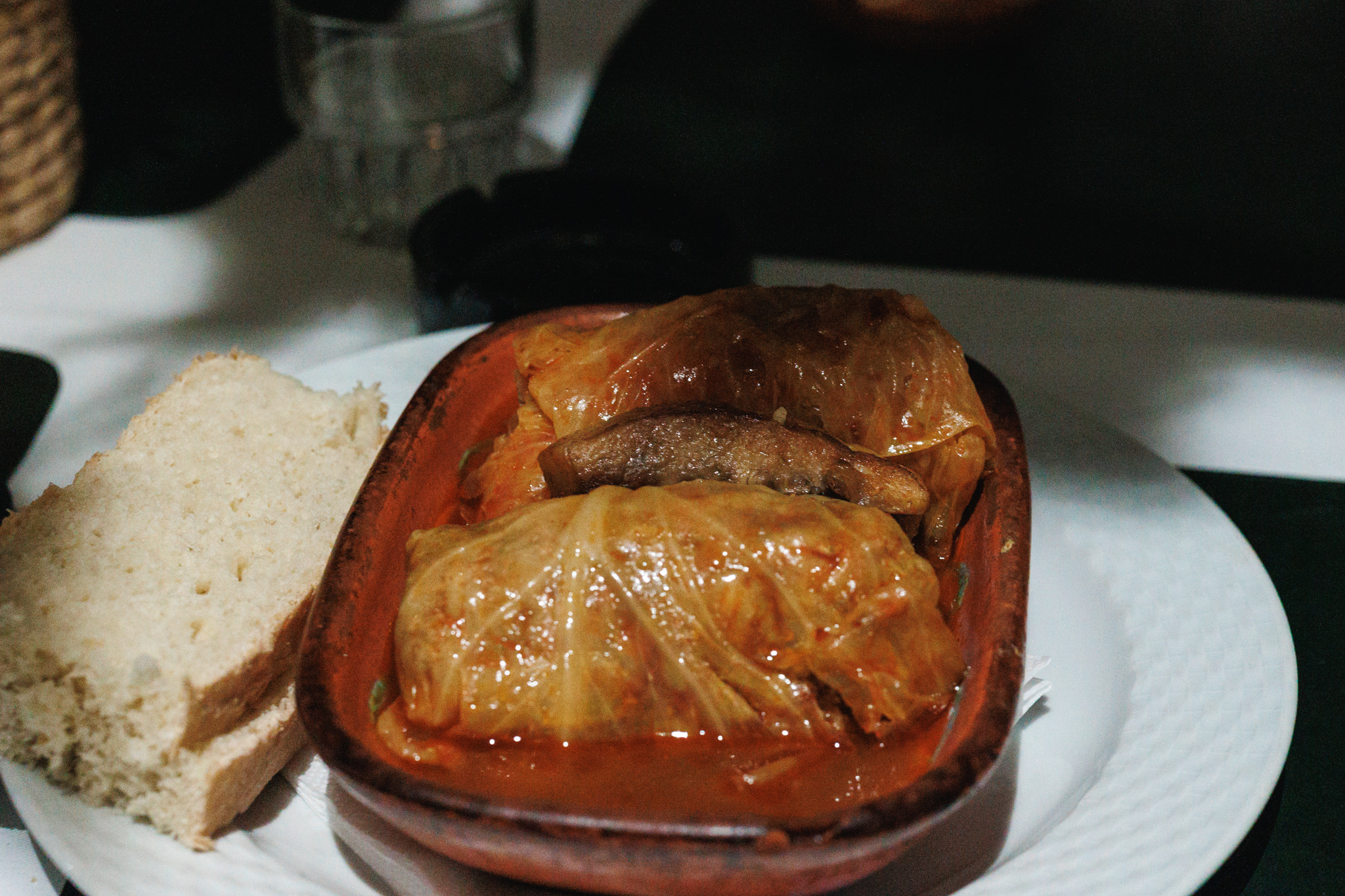 Two large sarma cabbage rolls with a sausage between them, served with bread at Resto bar Greda in Novi Sad.