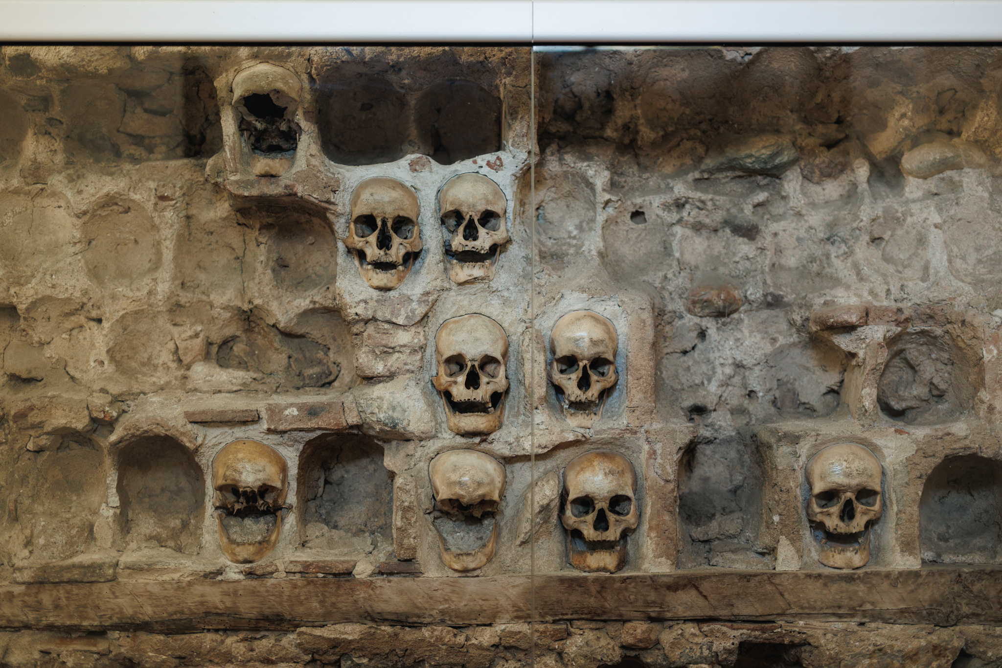 Human skulls set in niches in the stone wall of Skull Tower in Niš, with many of the niches around them empty