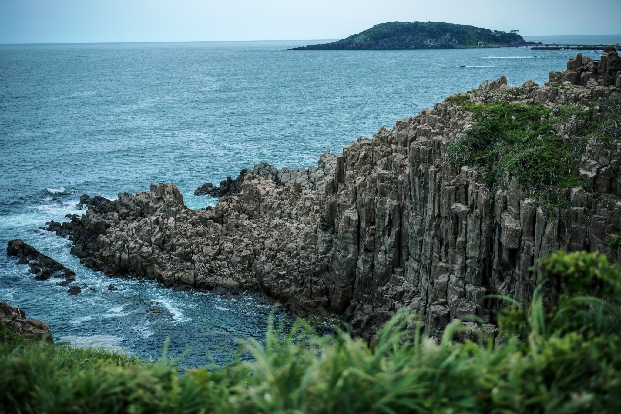 Columnar cliffs of Tojinbo rising above the Sea of Japan in Fukui, with Oshima visible across the water.