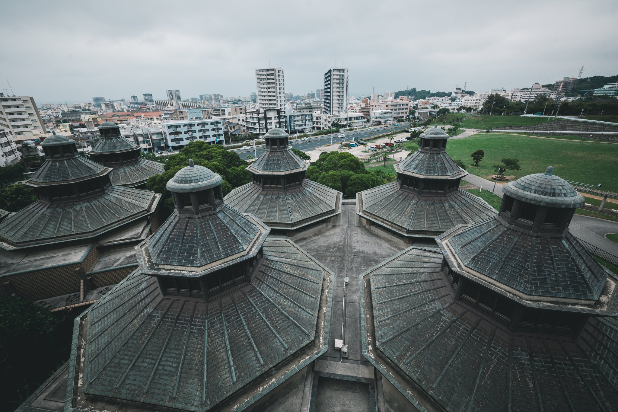 Looking down from the observation tower at clustered octagonal roofs, most with a smaller lantern on top, with apartment blocks and a park beyond
