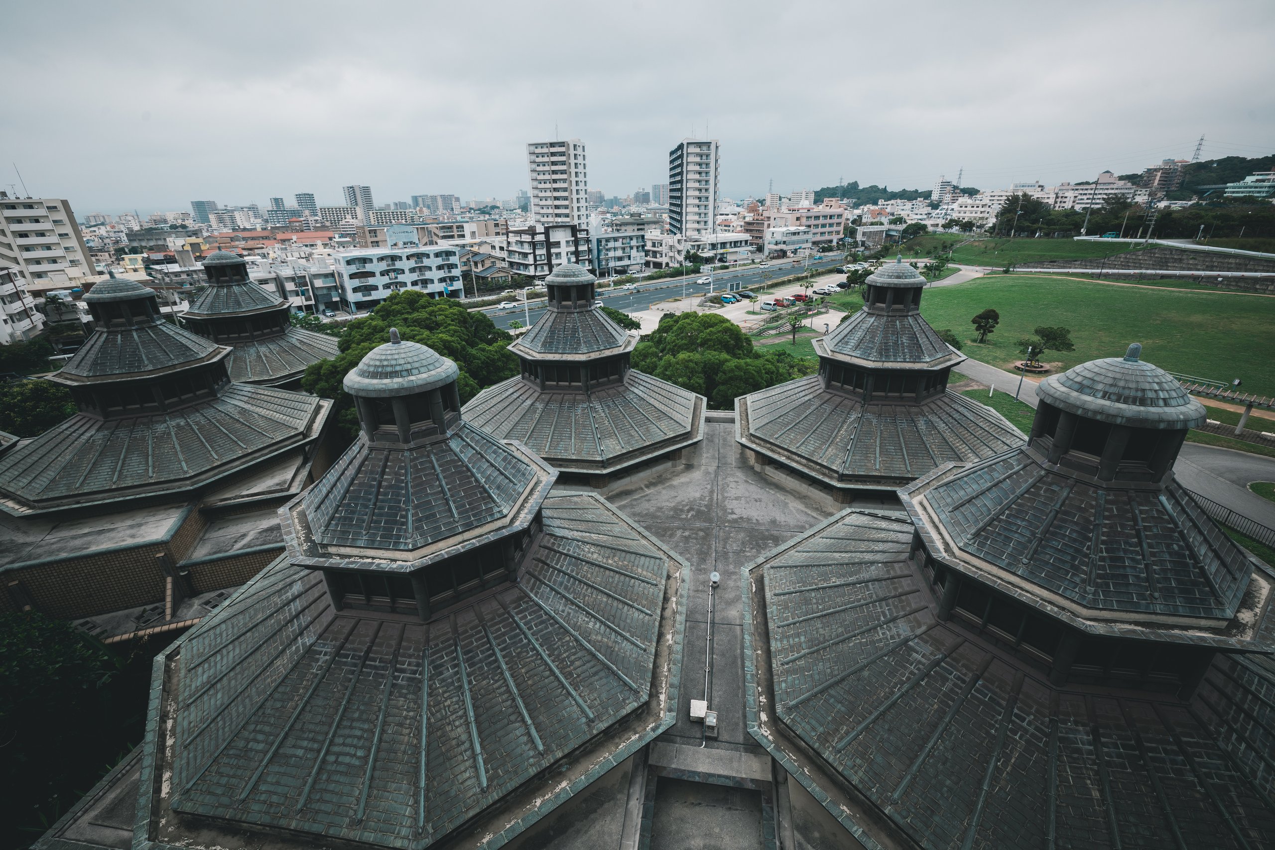 Looking down from the observation tower at clustered octagonal roofs, most with a smaller lantern on top, with apartment blocks and a park beyond
