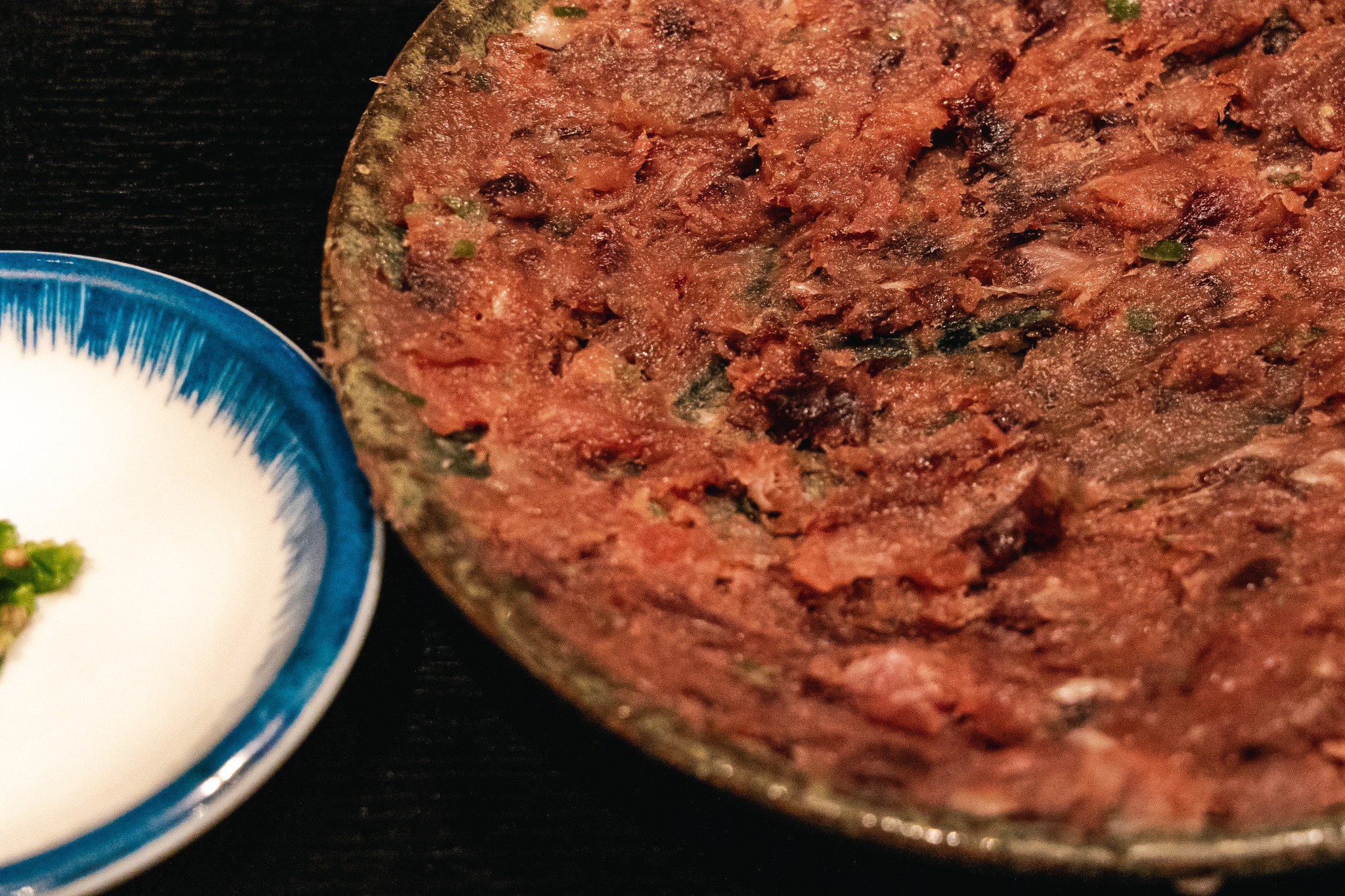 Close view of finely chopped dark-red uzuwa spread across a plate.